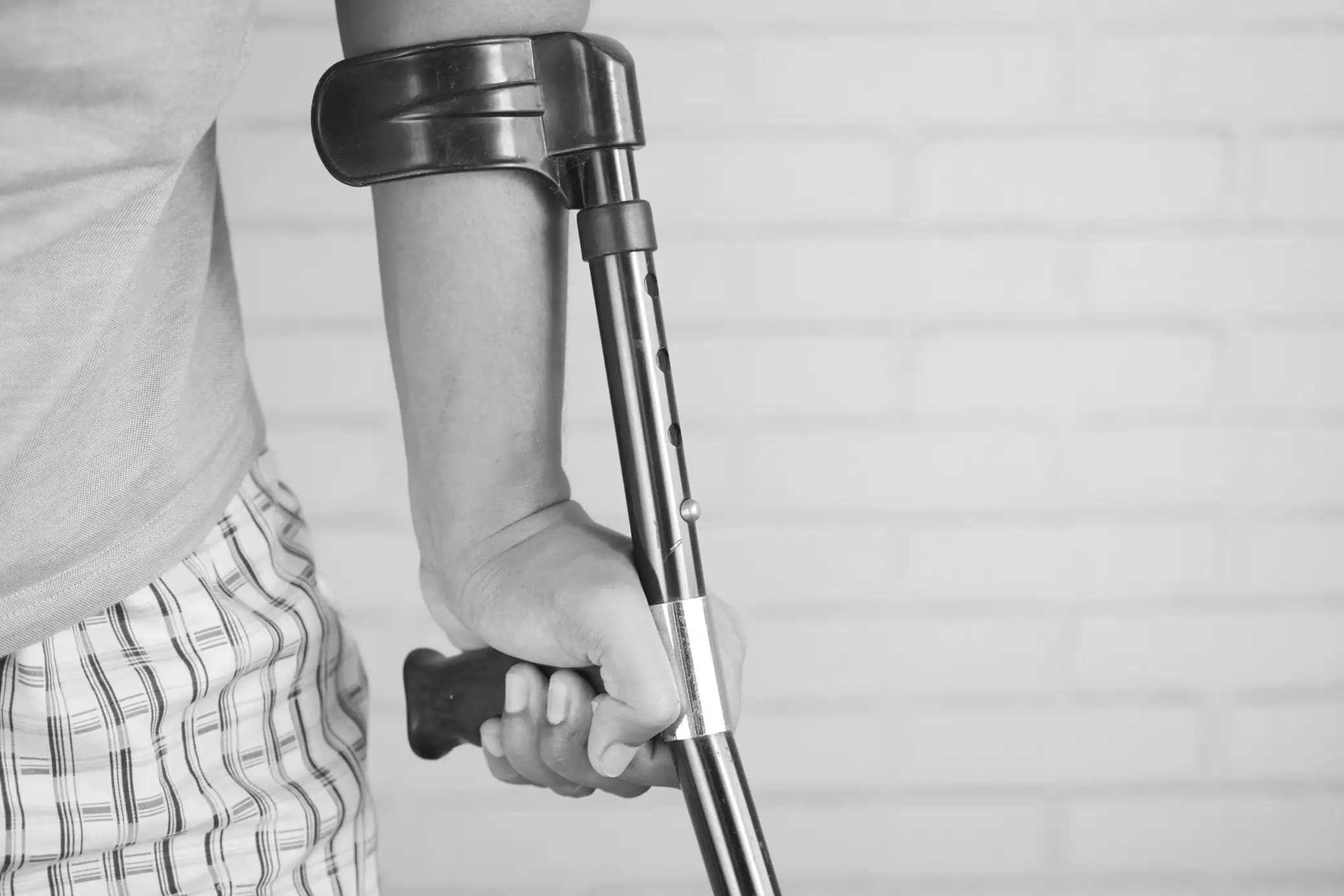 Grayscale Photo of Person with Crutches